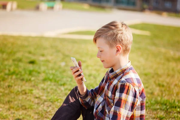 Barn leker telefonen utomhus i soliga dag. — Stockfoto