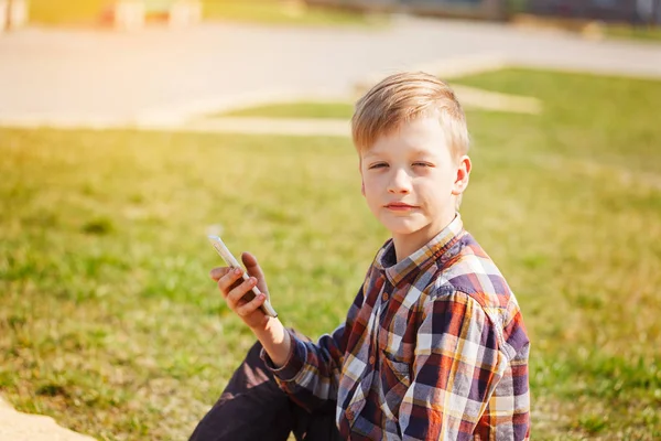 Barn leker telefonen utomhus i soliga dag. — Stockfoto