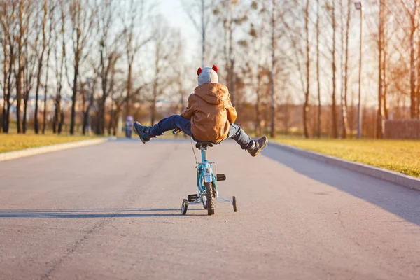 Rapaz a andar de bicicleta na estrada de asfalto num dia ensolarado. Visão traseira . — Fotografia de Stock