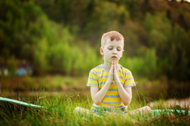 Doğa arka plan üzerinde yoga yaparken yakışıklı. Sportif küçük çocuk yaz Park yapıyor.