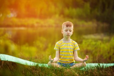 Doğa arka plan üzerinde yoga yaparken yakışıklı. Sportif küçük çocuk yaz Park yapıyor.