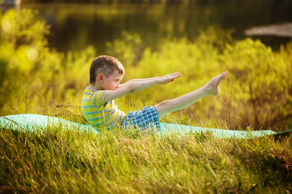 Sevimli çocuk spor doğa arka plan üzerinde yapıyor. Sportif küçük çocuk yaz Park yapıyor.