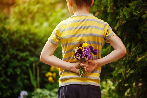 Child hands holding a bouquet pansies flower . Back view.Focus for flowers — Stock Photo, Image