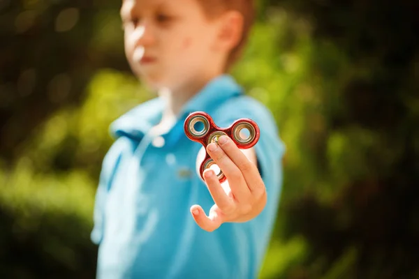 Schattige kleine jongen spelen met fidget hand spinner in zomerdag. Populaire en trendy speelgoed voor kinderen en volwassen. — Stockfoto