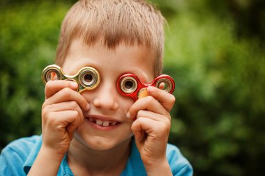 Yaz günü topluca el spinner ile oynayan sevimli küçük çocuk. Yetişkin ve çocuklar için popüler ve modaya uygun oyuncak.