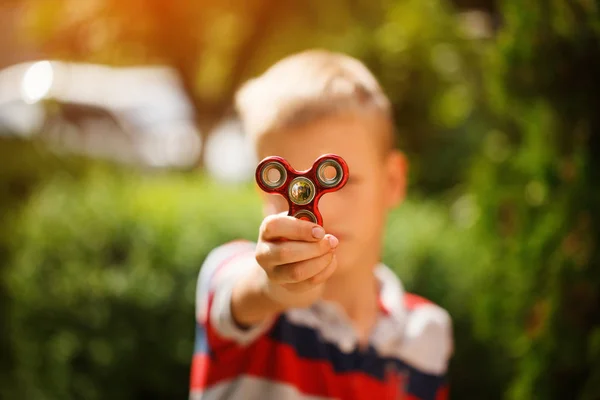 Schoolboy holds a spinner fidget in his hands. Trendy and popular toy for children and adult. — Stock Photo, Image