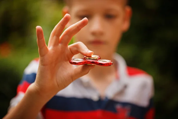 Schoolboy holds a spinner fidget in his hands. Trendy and popular toy for children and adult. — Stock Photo, Image