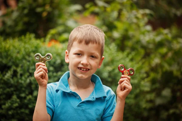 Milý chlapeček hraje s vrtět rukou číselník v letním dni. Populární a módní hračka pro děti a dospělé. — Stock fotografie