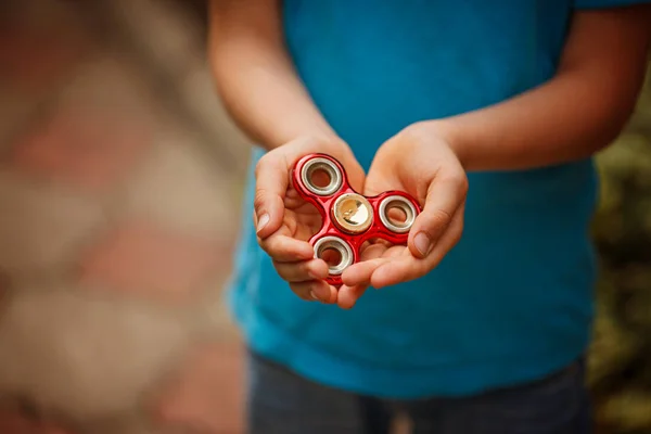 Cute little boy holds a spinner fidget in his hands. Trendy and popular toy for children and adult. — Stock Photo, Image