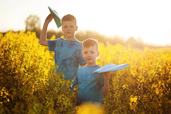 Two little boys friends with blue paper plane in summer yellow field. Brother love. Concept friendship. — Stock Photo, Image