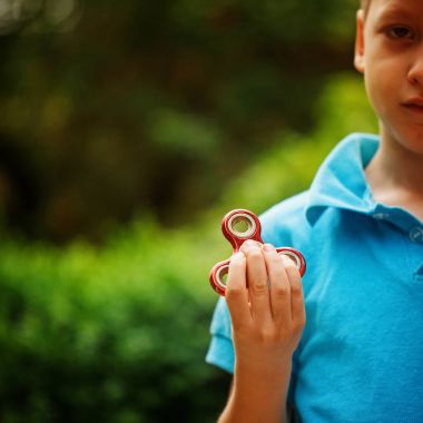 Yaz günü topluca el spinner ile oynayan sevimli küçük çocuk. Yetişkin ve çocuklar için popüler ve modaya uygun oyuncak