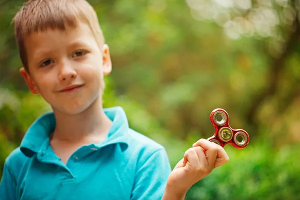 Ładny mały chłopiec bawi się fidget strony tarczy w letni dzień. Popularna i modna zabawka dla dzieci i dorosłych — Zdjęcie stockowe