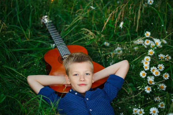 Porträt Teenager mit seiner Akustikgitarre im Gras liegend. — Stockfoto