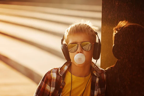 Tiener in sunglusses en hoofdtelefoon met kauwgom in zomer zonsondergang — Stockfoto