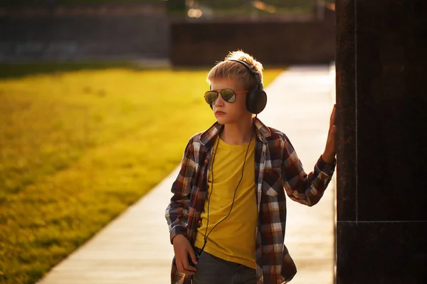 Guapo adolescente escuchando música y usando el teléfono al atardecer —  Fotos de Stock