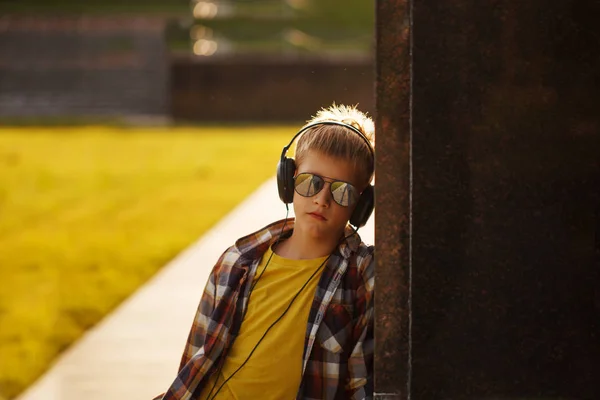 Guapo adolescente escuchando música y usando el teléfono al atardecer —  Fotos de Stock