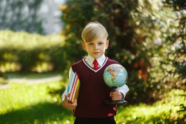 Netter Junge, der wieder zur Schule geht. Kind mit Büchern und Globus am ersten Schultag. — Stockfoto