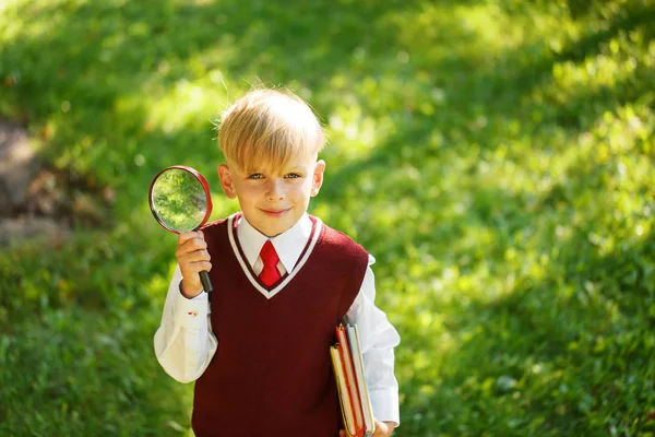 Cute boy going back to school. Child with books and loupe on first school day — Stock Photo, Image