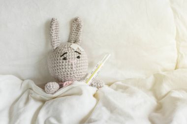 Hasta gri oyuncak tavşan termometre ve beyaz yatak odasında kafasına sıva ile.