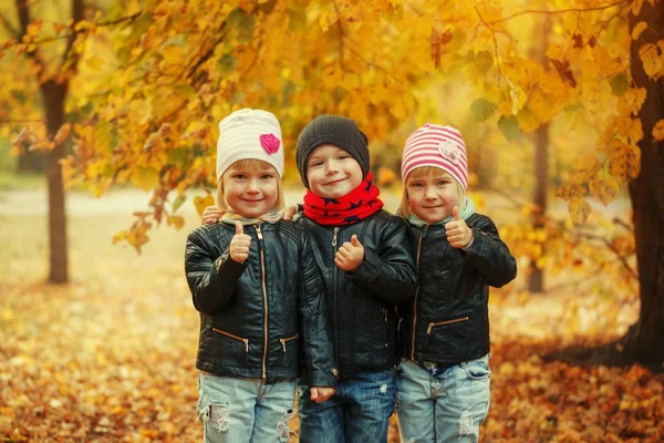 Three happy friends kids hugging and laughing in autumn park — Stock Photo, Image