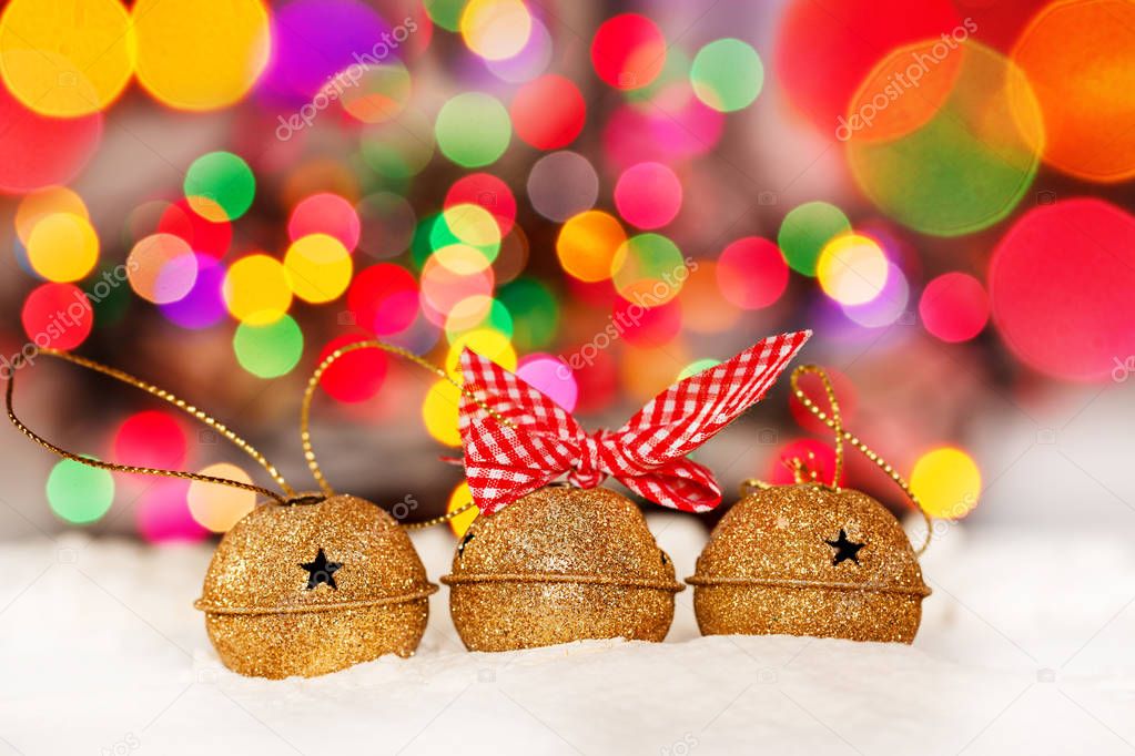 Greeting Christmas Card with Gold Jingle Bells on Colorful Bokeh Background.
