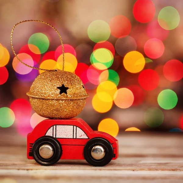 Miniaturní červené auto přepravující dar na střeše na bokeh barevné pozadí. Royalty Free Stock Fotografie