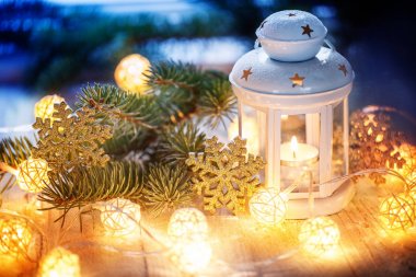 Beyaz Mum fener, köknar ağaç dalları ve aydınlık garland ile Noel dekorasyon.
