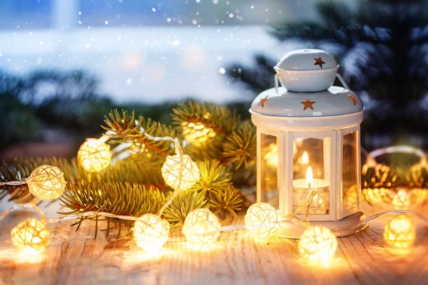 Christmas decoration with white candle lantern, fir tree branches and luminous garland. — Stock Photo, Image