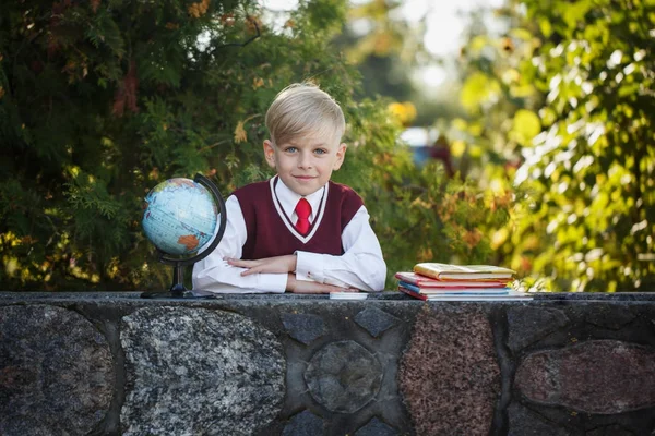 Liebenswerter Schuljunge mit Büchern und Globus im Freien. Bildung für Kinder. zurück zum Schulkonzept. — Stockfoto