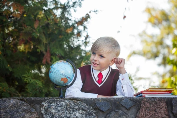 Очаровательный школьник с книгами и глобусом на открытом воздухе. Образование для детей. Снова в школу . — стоковое фото
