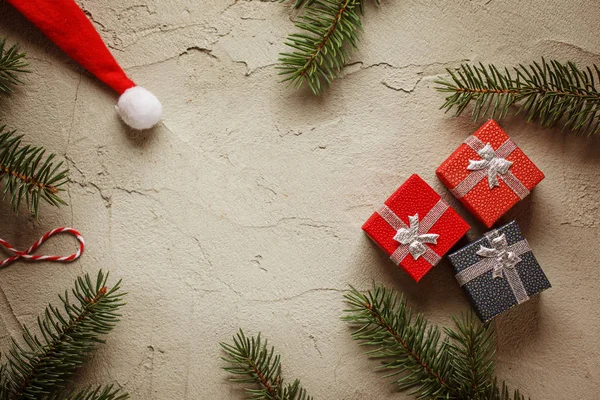 Karácsonyi kis díszdobozok szürke háttér, a fenyő ágak. Karácsonyt és boldog új évet összetétele. Szemközti nézet. — Stock Fotó