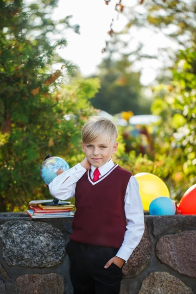 Liebenswerter Schuljunge mit Büchern und Globus im Freien. Bildung für Kinder. zurück zum Schulkonzept. — Stockfoto