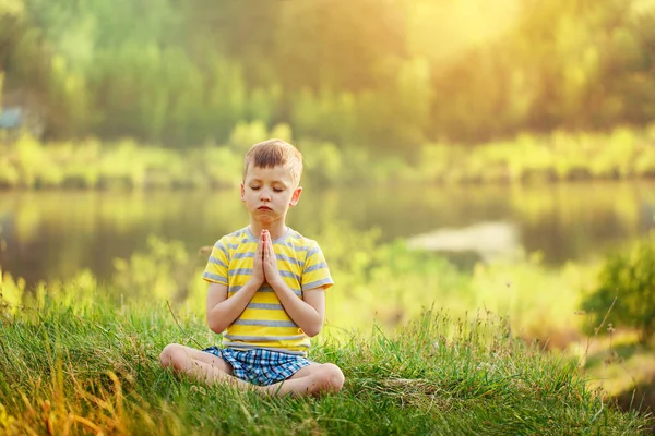 Little cute boy practicing yoga pose on a mat in spring day — Stock Photo, Image