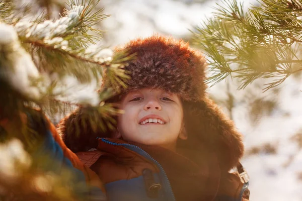Happy child walking in a winter forest in sunny day — Stock Photo, Image