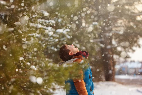 Lindo niño cogiendo copos de nieve con su lengua mientras camina en invierno día soleado . — Foto de Stock