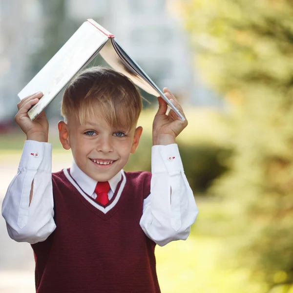 Porträtt liten skolpojke på natur bakgrund. Barn med böcker — Stockfoto