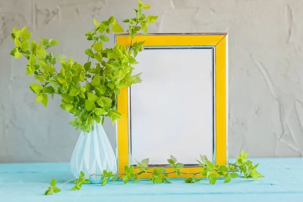 Yellow frame mockup and vase with fresh green branches.