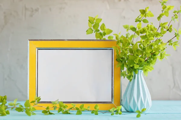 Yellow frame mockup and vase with fresh green branches.
