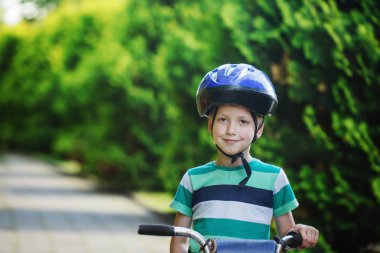 Portre, asfalt yol yaz parkta bisikletle kask içinde küçük çocuk.