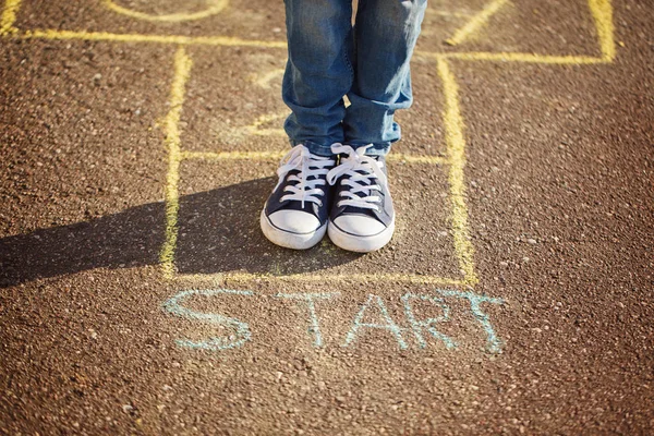 Gros plan des jambes du garçon et jouer au marelle sur le terrain de jeu à l'extérieur. Hopscotch populaire jeu de rue — Photo