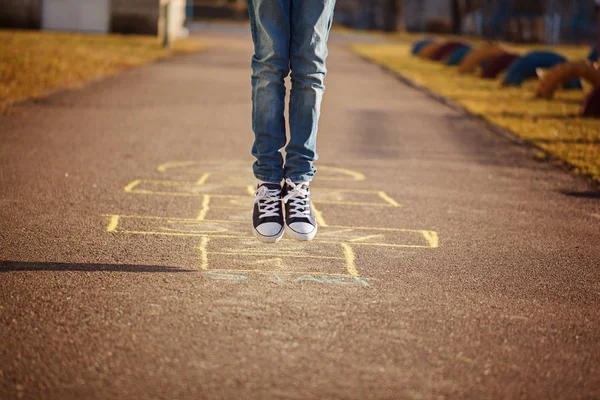 Gros plan des jambes du garçon et jouer au marelle sur le terrain de jeu à l'extérieur. Hopscotch populaire jeu de rue — Photo