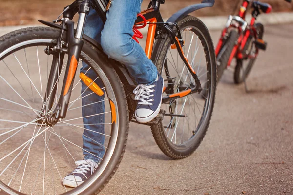 Criança em uma bicicleta na estrada de asfalto no dia de primavera ensolarado. Fechar o pedal e o pé — Fotografia de Stock