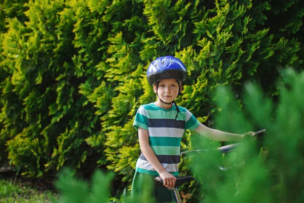 Portrait little boy in helmet on a bicycle at asphalt road in the summer park — Stock Photo, Image