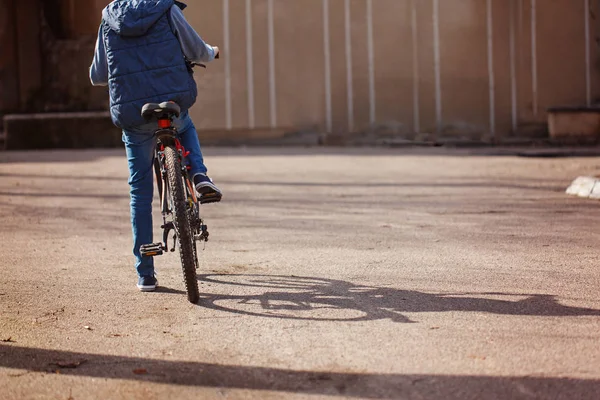 Niño en una bicicleta en la carretera de asfalto en el soleado día de primavera. Volver vie — Foto de Stock