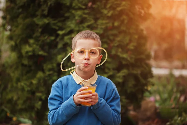 Portrait Happy child drinking orange juice in summer day. — Stock Photo, Image