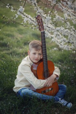 Yakışıklı çocuk yaz gün çimlere oturup gitar çalmak müzik yapma