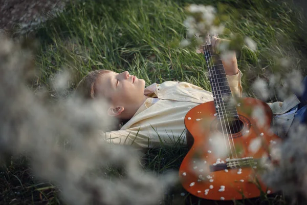 Netter Junge Liegt Mit Einer Gitarre Gras Bei Sonnenuntergang — Stockfoto