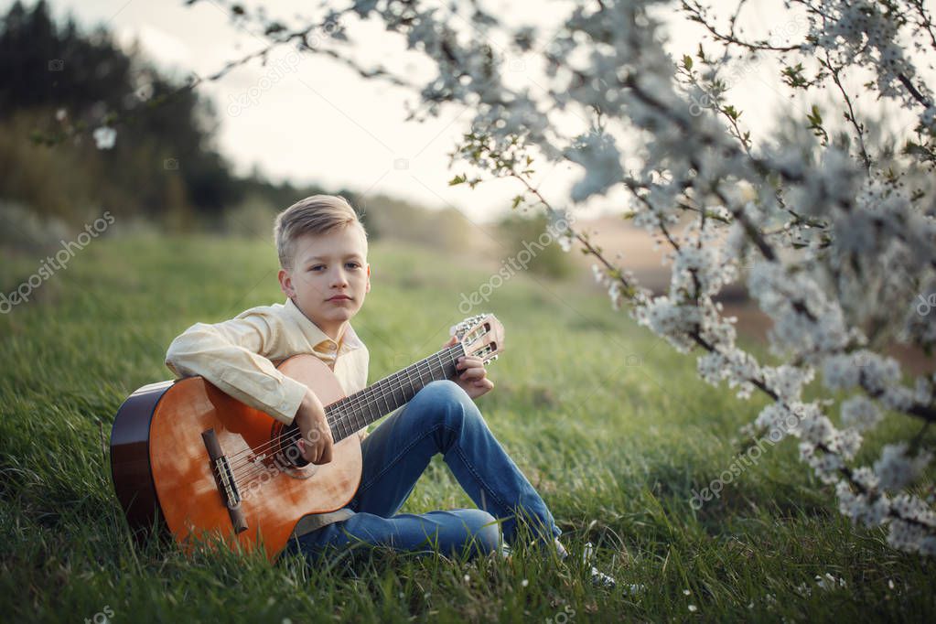 Cute boy making music playing the guitar on nature