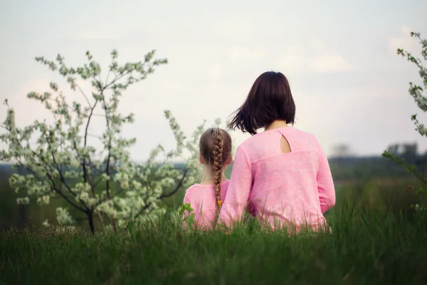 Anne ve yaz günde çimlere oturup onun küçük dauther. Bir arkadan görüntülemek.