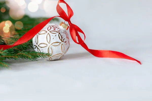 Vánoční dovolená složení s bílou kuličkou a červenou stuhou na světlém pozadí s kopírovacím prostorem — Stock fotografie